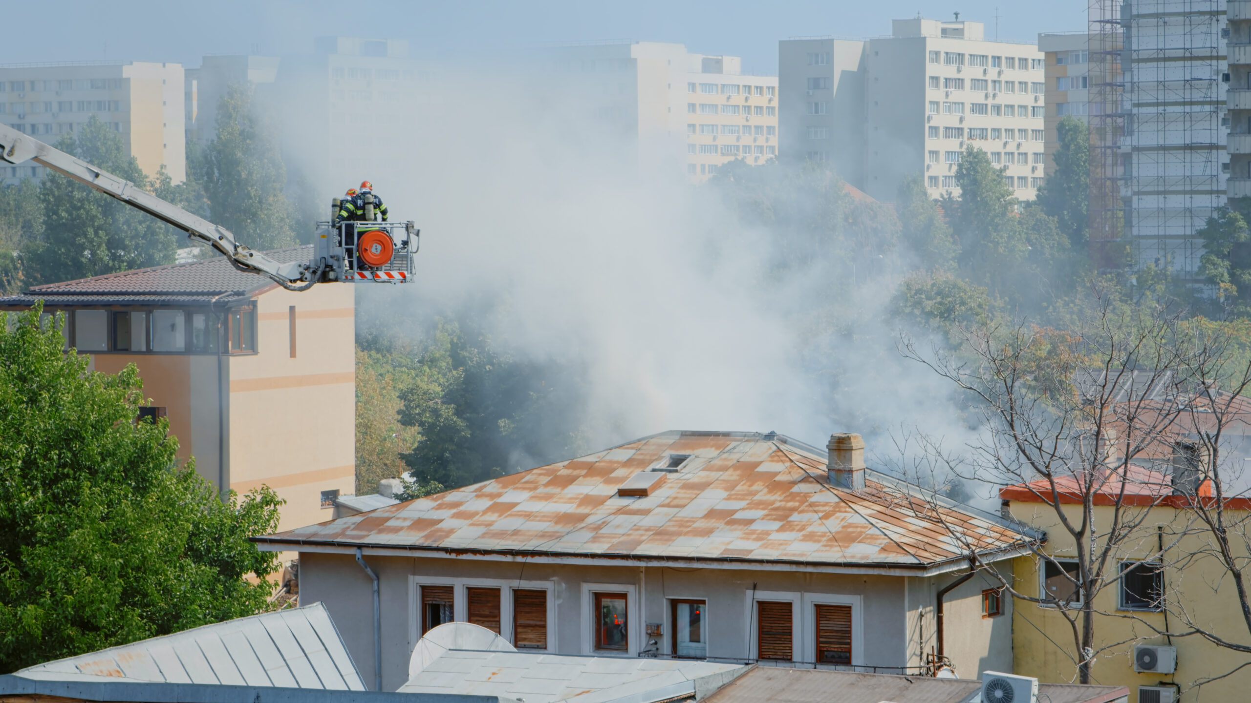 close-up-firefighters-platform-truck-helping-with-fire-from-burning-building-firemen-with-equipment-water-working-extinguish-flames-roof-house-city-landscape Ensuring Safety During Fire Season
